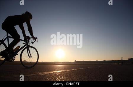 Berlin, Deutschland. 18 Feb, 2019. Mit der untergehenden Sonne und strahlend blauem Himmel, ein Radrennfahrer macht seine Runden auf dem ehemaligen Flughafen Berlin-Tempelhof bei Temperaturen um die 13 Grad. Quelle: Wolfgang Kumm/dpa/Alamy leben Nachrichten Stockfoto