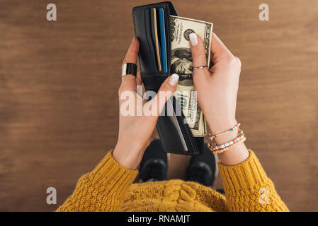 Blick von oben auf die Frau von der Brieftasche Dollar Banknoten auf hölzernen Hintergrund Stockfoto