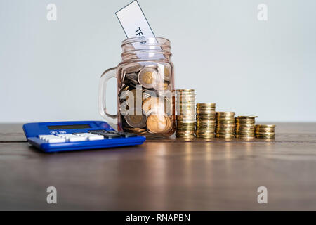 Jar von Münzen mit Taschenrechner angezeigt Einsparungen ein Steuerfreies Sparkonto Stockfoto