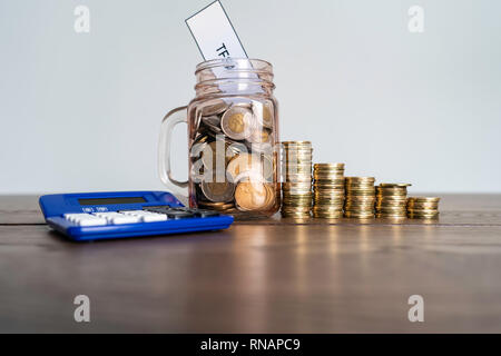 Jar von Münzen mit Taschenrechner angezeigt Einsparungen ein Steuerfreies Sparkonto Stockfoto