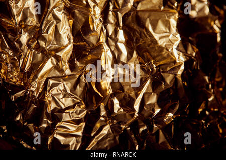 Zerknitterte goldene Folie mit Twinkles in Schatten Stockfoto