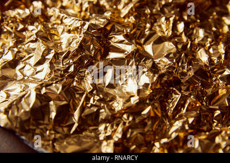 Zerknitterte goldene Folie mit Twinkles auf braune Oberfläche Stockfoto