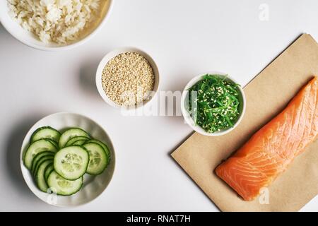 Frische Meeresfrüchte Rezept. Garnelen Lachs poke Schüssel auf Handwerk Papier, Chuka Salat, weißer Reis, Gurken, Portioniert mit weißer Sesam. Essen Konzept poke Schüssel Stockfoto