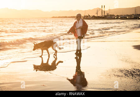 Schönen Ruhestand ältere Frau und pet-deutscher schäferhund Hund wandern entlang der Küste Meer Ozean am Strand in Begleitung Nutzen der Tiere aktiv halten Stockfoto