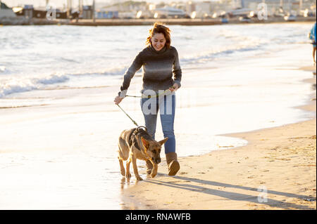 Schönen erwachsenen Frau und pet Deutscher Schäferhund hund Wandern entlang der Küste Meer Ozean am Strand bei Sonnenuntergang am Nachmittag in Begleitung von Tieren t Stockfoto