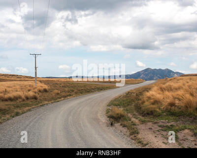 Power Pole Position auf einer Kurve von einem unverschlossenen Schotterstraße, tussock Land, Ngamatea Station, Inland Mokai Patea, Central North Island, Neuseeland Stockfoto