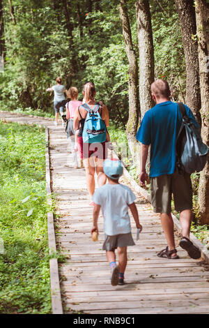 Familie gehen, ein Weg in den Wald. Mutter, Vater, Jungen und Mädchen Zeit miteinander zu verbringen, Urlaub in der Natur Stockfoto