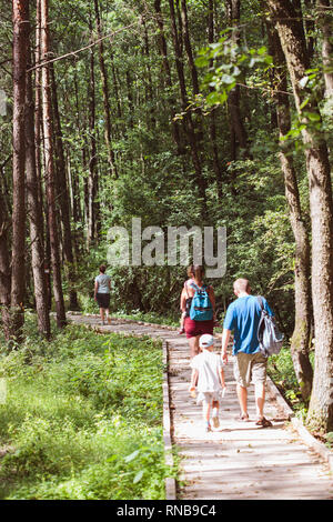 Familie gehen, ein Weg in den Wald. Mutter, Vater, Jungen und Mädchen Zeit miteinander zu verbringen, Urlaub in der Natur Stockfoto