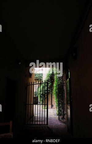 Blick auf das Tor in den Innenhof durch den dunklen Tunnel arch Stockfoto