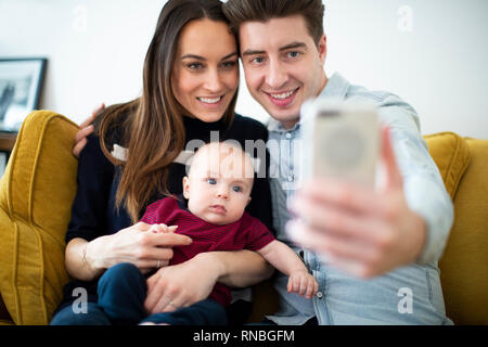 Familie sitzt auf dem Sofa zu Hause Posieren für Selfie auf Handy Stockfoto