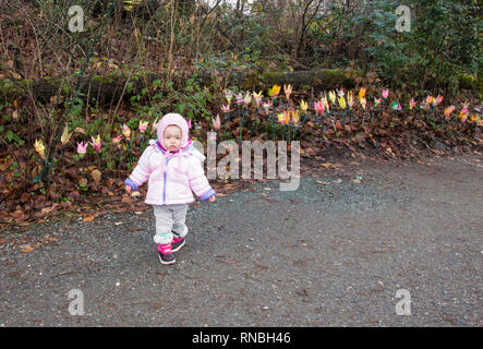 18 Monate altes Baby mit der Weihnachtsbeleuchtung bei einem schönen Spaziergang im Park. Kleinkind Mädchen alle Rosa winter Outfit außerhalb tragen Stockfoto