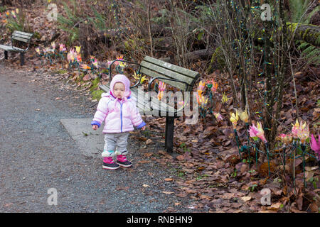 18 Monate altes Baby mit der Weihnachtsbeleuchtung bei einem schönen Spaziergang im Park. Kleinkind Mädchen alle Rosa winter Outfit außerhalb tragen Stockfoto