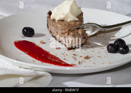 Chocolate Chip cheesecake Slice auf Platte mit Blaubeeren und couli Stockfoto