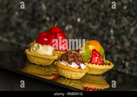 Vier dessert Torten auf Schwarz reflektierende Bench Top gewinkelt Stockfoto