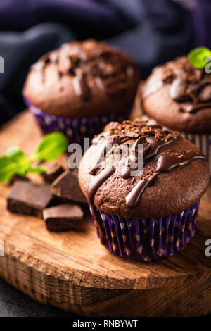 Schokolade Kuchen mit Schokolade und minzeblatt auf Holz, das Board eingerichtet. Detailansicht. Leckere Schokolade Muffins oder Cupcakes Stockfoto