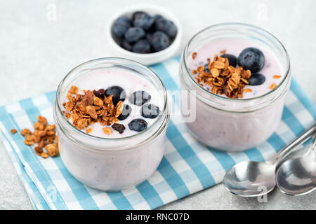 Heidelbeere Joghurt mit Müsli in den jar auf hell blau kariert Serviette. Detailansicht. Gesundes Essen, gesundes Essen Konzept Stockfoto