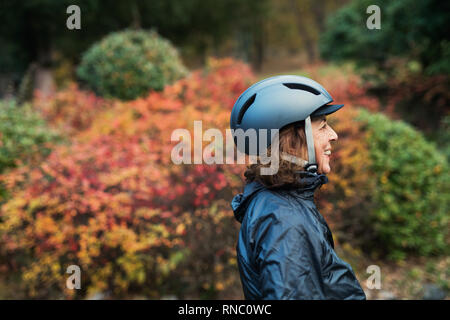 Seitenansicht eines Active Senior Frau mit fahrradhelm stehen draußen in der Natur. Stockfoto