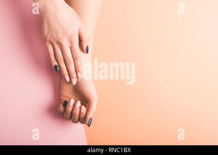 Blick auf weibliche Hände mit den rosa und schwarzen Nägel auf bicolor Hintergrund, Farbe 2019 Konzept 7/8 Stockfoto