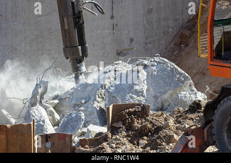 Nahaufnahme des Hydraulikhammers der Abriss Bagger bei der Arbeit mit Staub und Fliegen konkrete Partikel Stockfoto