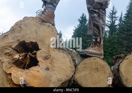 Hiker's Stiefel während Wanderer stehen auf Protokolle Stockfoto