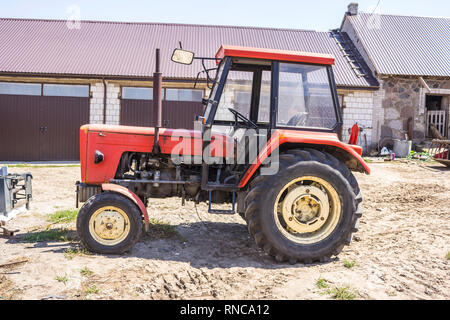 Alten Traktor für Arbeiten in einem Bereich, wo Mais und Gras für die Kühe gezüchtet. Seitenansicht einer landwirtschaftlichen Maschine. Ausrüstung für eine Molkerei. Stockfoto