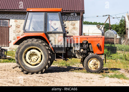 Alten Traktor für Arbeiten in einem Bereich, wo Mais und Gras für die Kühe gezüchtet. Seitenansicht einer landwirtschaftlichen Maschine. Ausrüstung für eine Molkerei. Stockfoto