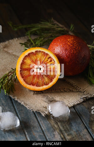 In Scheiben geschnitten und ganze Reifen saftigen Blutorangen und Eis auf Holz- Hintergrund. Stockfoto