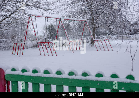 Schaukeln im Schnee auf der leeren Kinderspielplatz abgedeckt Stockfoto