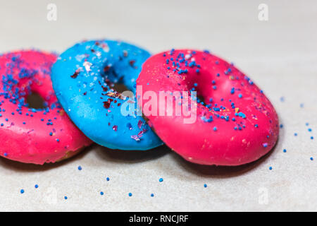 Blau und Rosa glasierten Krapfen mit Streuseln auf hellen Hintergrund, Nahaufnahme. Stockfoto