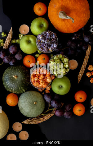 Grün, Lila und orange gefärbt Popcorn und Frucht Mix auf einem dunklen Hintergrund Stockfoto