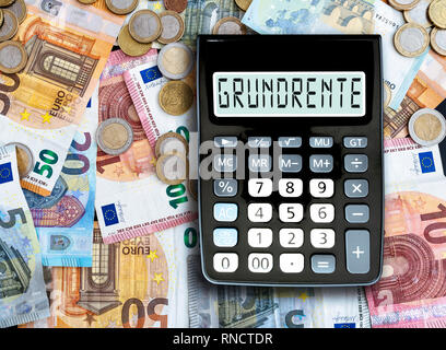 Deutsche Wort Grundrente (Basic Pension) auf Anzeige von Taschenrechner gegen bares Geld auf den Tisch geschrieben Stockfoto