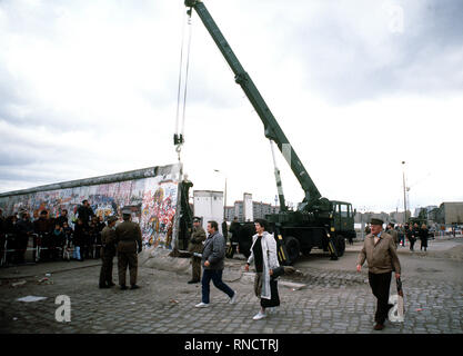 Ost-berliner überqueren auf den Westen als ein Kran ist die Berliner Mauer am Potsdamer Platz zu demontieren. Stockfoto