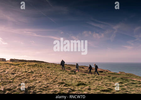 Eine Gruppe von Wanderern und ein Hund einen Spaziergang entlang des South West Coast Path an der Küste von North Cornwall am späten Nachmittag Licht. Stockfoto