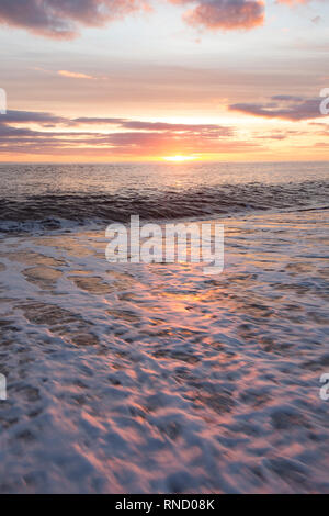 Eine Ansicht von Chesil Beach in der Nähe von Abbotsbury im Februar auf den Sonnenuntergang mit schäumenden Wellen durch starke Winde gerührt, ein paar Tage vor, in der foregrou Stockfoto