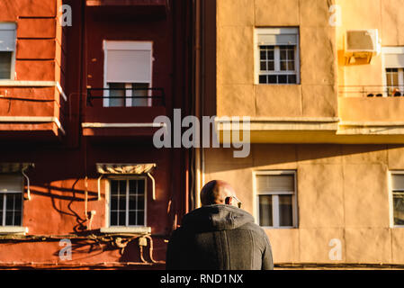 Schwarzer Mann, mit kahl rasierten Kopf, auf dem Rücken und sitzen vor der alten Gebäude Stockfoto