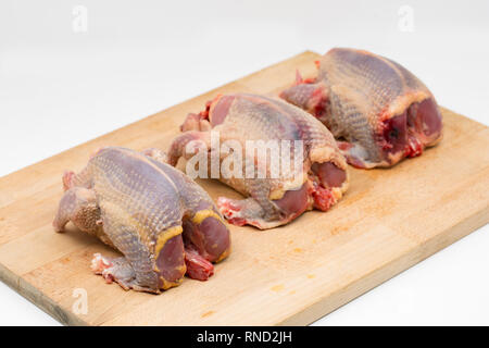 Drei gerupft und vorbereitet ungekocht woodpigeons auf einer hölzernen Schneidebrett und weißen Hintergrund. Die woodpigeon, Columba Palumbus, ist einer von Großbritanniens Stockfoto