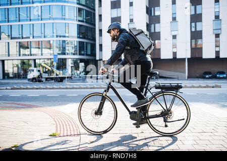 Männliche Kurier mit dem Fahrrad die Auslieferung von Paketen in der Stadt. Kopieren Sie Platz. Stockfoto