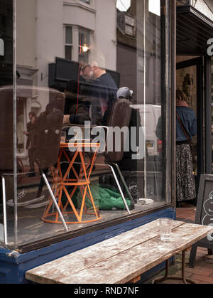 Man genießt Kaffee durch Fenster in Cafe in Brighton Lanes, Reflexion durch das Fenster. Stockfoto