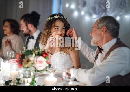 Ein liebevoller Vater und schöne Braut am Tisch sitzen auf einer Hochzeit, zu sprechen. Stockfoto