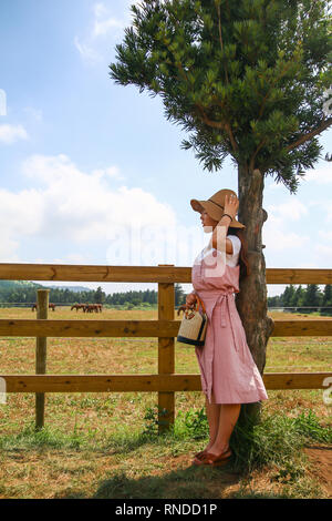 Asiatische junge Frau wartet auf jemand durch den Zaun in der Ranch Stockfoto