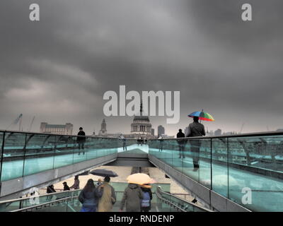 Mann mit bunten Regenschirm auf dem Millenium Birdge und St. Paul's Kathedrale im Hintergrund - London - UK Stockfoto