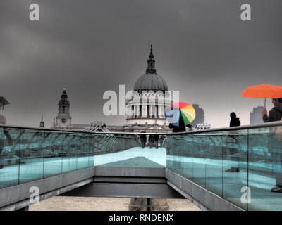 Mann mit bunten Regenschirm auf dem Millenium Birdge und St. Paul's Kathedrale im Hintergrund - London - UK Stockfoto