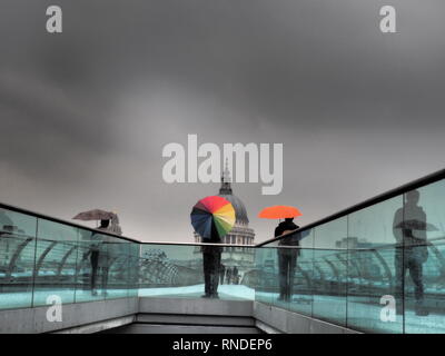 Mann mit bunten Regenschirm auf dem Millenium Birdge und St. Paul's Kathedrale im Hintergrund - London - UK Stockfoto