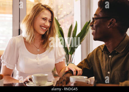 Junge Frau treffen mit ihrem Freund im Coffeeshop. Happy interracial Paare zusammen im Cafe sitzen. Stockfoto