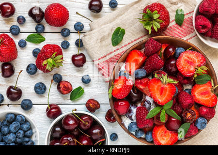Joghurt mit frischen Himbeeren, Erdbeeren, Kirschen und Heidelbeeren mit Chia Samen. gesundes Frühstück. top View Stockfoto