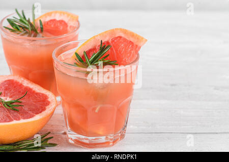 Grapefruit Cocktails in Gläsern mit Rosmarin und Eis auf weißem Hintergrund. Gesund Zitrusfrüchte Sommer trinken. Nach oben Schließen Stockfoto
