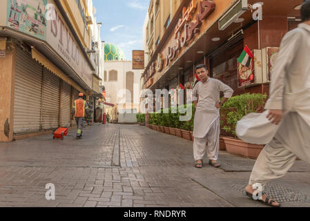 Pakistanische Männer wandern und starrte auf die Kamera in einer ruhigen Straße des beliebten und ethnischen Stadtteil Deira in Dubai, Vereinigte Arabische Emirate, Stockfoto