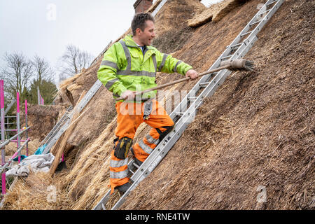 Cambridgeshire, Großbritannien. 18 Feb, 2019. Die strohgedeckten Dach einer alten Ferienhaus Bauernhaus auf Lark Rise Farm wird repariert. Chris Pepper und sein Team arbeiten das denkmalgeschützte Gebäude zu rethatch, Teile aus dem 14. Jahrhundert stammt. Der erfahrene Handwerker mit langem Stroh der Grat wieder aufzubauen und die wichtigsten Teile des Dachs. Credit: Julian Eales/Alamy leben Nachrichten Stockfoto