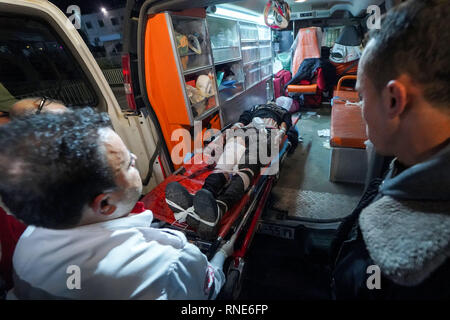 Gaza, Palästina. 18 Feb, 2019. Eine verletzte Demonstrator liegen auf einer Bahre gesehen ins Krankenhaus gebracht werden Behandlung während der Auseinandersetzungen zu erhalten. palästinensische Demonstranten, die sich selbst die "Nacht der Verwirrung Einheiten'' in Brand gesetzt, wie sie in der Nähe der Gaza-Israel Grenze östlich von zentralen Gazastreifen sammeln. Die so genannte "Nacht der Verwirrung Einheiten'' auch mit israelischen Truppen entlang des Sicherheitszauns zusammengestoßen, nach etwa zwei Monaten ohne solche nächtlichen Scharmützel. Credit: Mohamed Zarandah/SOPA Images/ZUMA Draht/Alamy leben Nachrichten Stockfoto