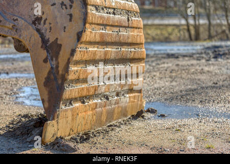 Nahaufnahme der angeschlossenen Bagger Schaufel und Eimer Zähnen ruht auf dem Boden im Freien Stockfoto